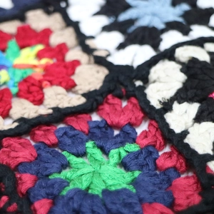 Macro shot of colorful granny square crochet fabric with handmade fringed tassels