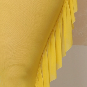 Detail shot of bright yellow mesh beach pants featuring delicate ruffle hem edges