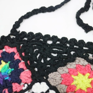 Close-up of colorful handmade crochet floral pattern with black braided straps detail