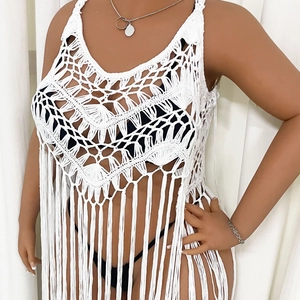 Detail view of white crochet beach cover-up featuring fringe hem and geometric patterns