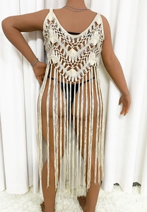 Detail of white crochet cover-up with intricate hollow-out patterns and long tassels