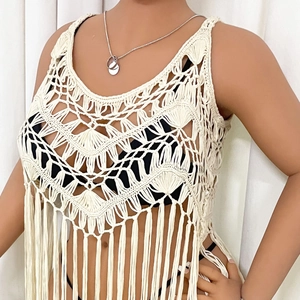 Detail of crochet knit patterns and long fringe on a cream beach cover-up vest