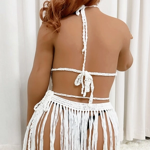 Detail of white crochet knit beach set featuring tassel skirt and backless halter top