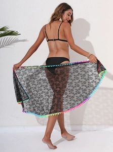 Detail of sheer black floral lace sarong featuring colorful pom-pom trim and tassel hem