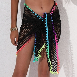 Détail d'un paréo de plage en résille noire avec pompons colorés et fermeture nouée