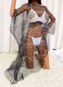 Détail d'un cache-maillot en mesh marbré noir et bikini au crochet blanc sur tapis doux