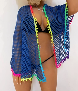 Detail of blue crochet mesh beach cover-up featuring vibrant rainbow pom-pom trim on edges