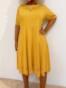 Detail of yellow short-sleeve dress featuring intricate laser-cut floral patterns