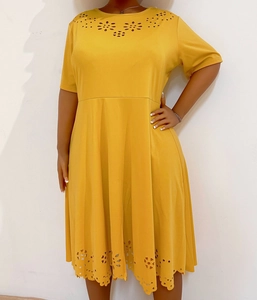 Detail of laser-cut floral patterns on the neckline and hem of the yellow dress