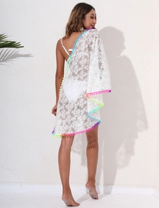 Detail of white floral lace beach cover-up featuring vibrant colorful pom-pom fringe trim