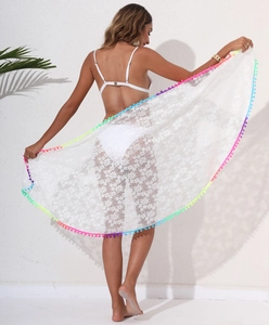 Close-up of white floral lace beach shawl with vibrant rainbow pom-poms on the edges