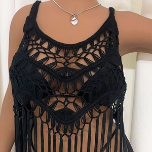 Close-up of black crochet knit vest featuring geometric hollow patterns and long tassels