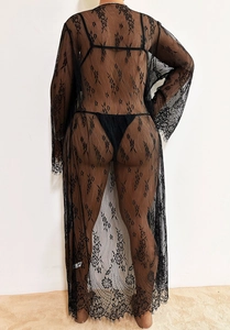 Détail du motif en dentelle florale et du tissu transparent sur ce long cardigan noir de plage