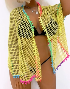 Detail of yellow crochet beach cover-up with colorful pom-pom tassels and mesh design