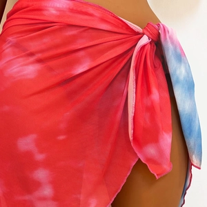 Macro view of tie-dye mesh beach sarong with side knot detail and vibrant red patterns