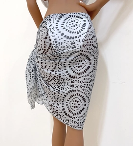 Macro detail of semi-transparent white beach sarong with black abstract polka dot print