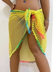 Detail of yellow crochet sarong with colorful pom-pom trim and hollow-out mesh texture