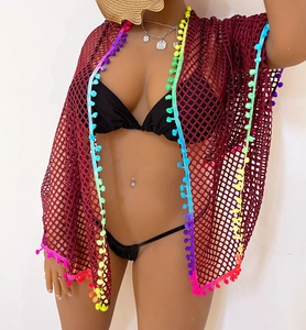 Detail of wine red crochet beach cover up with colorful rainbow pom-pom fringe trim