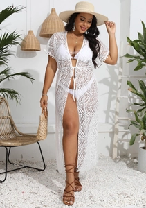 Dettaglio copricostume in pizzo bianco con motivi geometrici e finiture di nappe eleganti