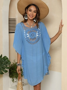 Détails d'une robe de plage au crochet bleu clair avec motifs tournesols et franges