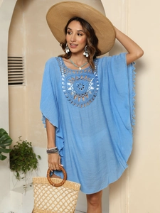 Détail de la robe de plage crochet bleu ciel avec des pompons à franges et motifs floraux