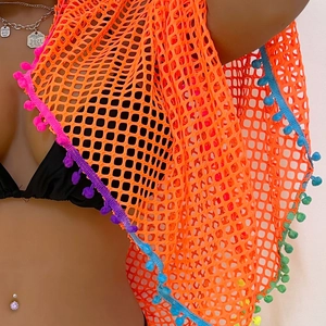 Close-up of orange mesh beach sarong with vibrant multi-colored pom-pom fringe detail