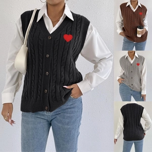 Detail of V-neck cable knit vest showing wooden buttons and red heart embroidery patch