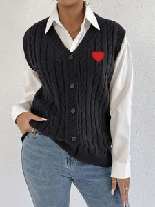 Detail of cable-knit vest with V-neck, brown buttons and a red heart patch embroidery