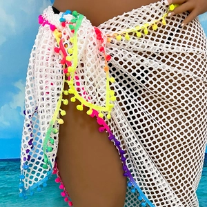 Detailed view of white mesh beach sarong with vibrant rainbow pom-poms on the hemline