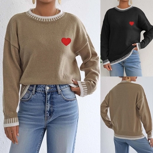 Detail of red heart embroidery and striped contrast collar on loose knit sweater