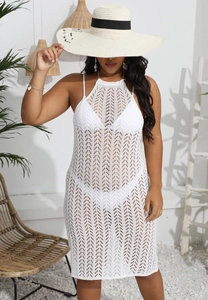 Détail d'une robe de plage en crochet blanc avec motifs en losange et encolure licou chic
