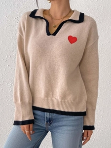 Detail of knit texture with red heart patch and contrast polo collar on women's sweater