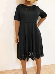 Detail of laser-cut floral patterns on the neckline and hem of a black short sleeve dress