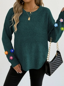 Detailed knit texture of dark green sweater with colorful crochet flower sleeves