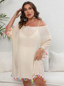 Détail de la robe de plage beige avec des pompons colorés sur les manches et l'ourlet