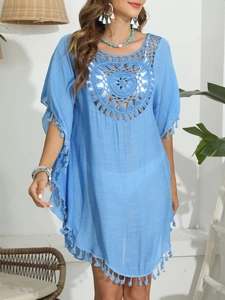 Gros plan sur une robe de plage en crochet bleu ciel avec détails de franges et fleurs