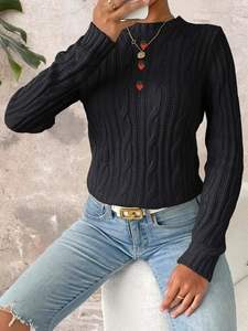 Detail of cable knit texture and red strawberry buttons on a black crewneck sweater