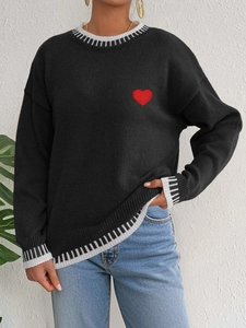 Close-up of red heart embroidery on black knit sweater with striped ribbed neckline