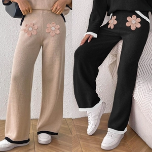 Dettaglio dei pantaloni in maglia con fiori 3D rosa e cuciture a contrasto sul fondo