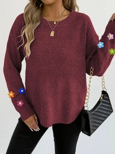 Detail view of burgundy knit sweater featuring colorful 3D floral patches on sleeves