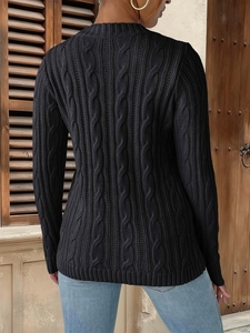 Women's black cable knit sweater with crew neck and ribbed cuffs in a scenic outdoor view