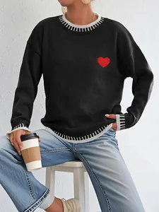 Close-up of red heart embroidery and black and white striped cuffs on knit sweater