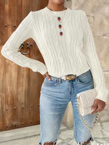 Detail of cream cable knit sweater with red strawberry button accents and quilted bag