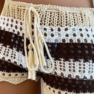 Detail of crochet knit texture with striped pattern and tassel drawstring on beach shorts