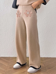 Dettaglio dei pantaloni in maglia con ricamo floreale rosa e bordi neri a contrasto in vita