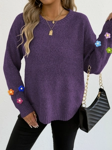 Close-up of colorful 3D crochet floral appliques on purple knit sweater sleeve