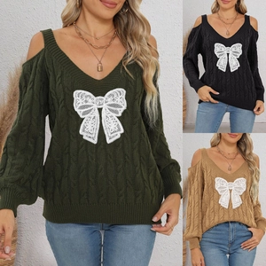 Detail of cable knit texture with lace bow on a v-neck cold-shoulder sweater