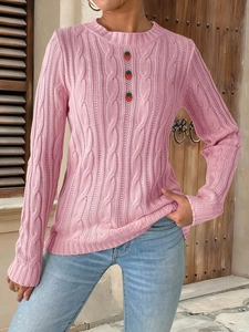 Detail of pink cable knit sweater featuring three 3D strawberry buttons on the chest