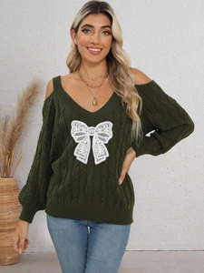 Detail of green knit sweater showing cable knit texture and white lace bow on the neckline