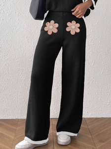 Dettaglio di pantaloni in maglia a gamba larga con fiori 3D rosa e perline